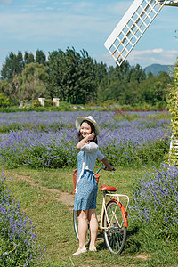 推着自行车的青年女人站在花海里图片