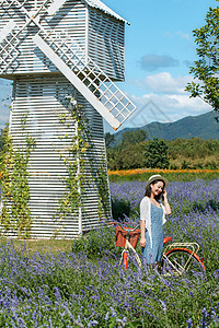 推着自行车的青年女人站在花海里图片