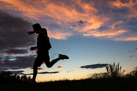 跑步动作剪影夕阳下跳跃的青年男人背景