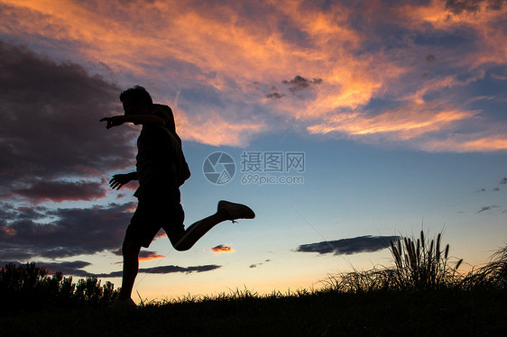 夕阳下跳跃的青年男人图片