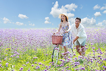 在花海里骑自行车的青年夫妇图片