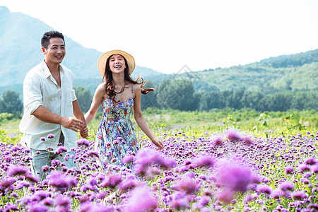 青年夫妇手牵手走在花海里图片