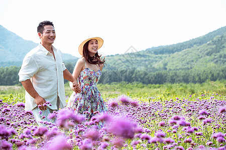 青年夫妇手牵手走在花海里图片