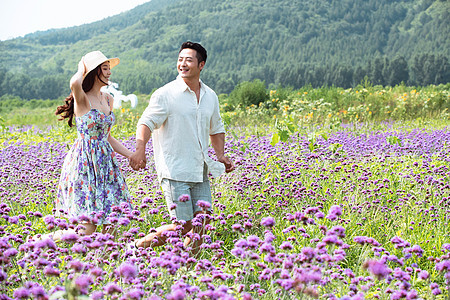 青年夫妇手牵手走在花海里图片