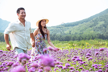 青年夫妇手牵手走在花海里图片