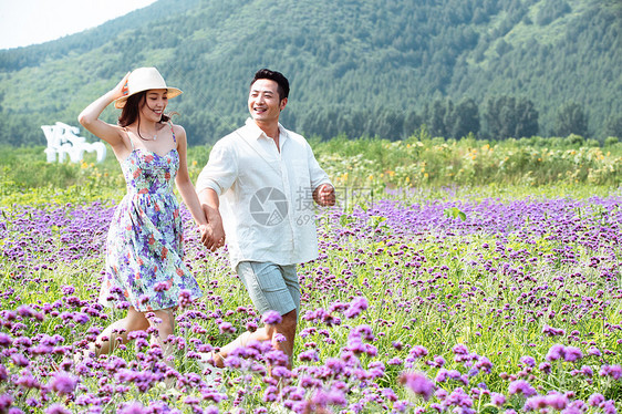 青年夫妇手牵手走在花海里图片