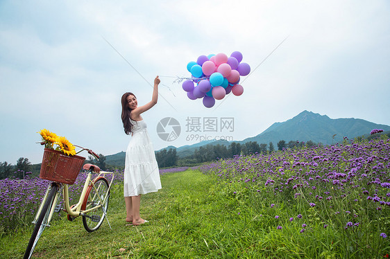青年女人在花海里拿着气球图片