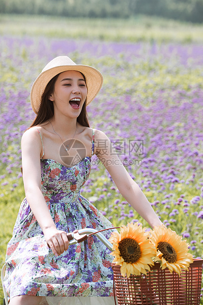 青年女人在花海里骑自行车图片