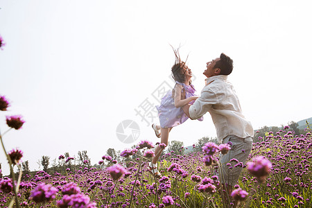 父女站在花丛里父亲抱着女儿在花丛中玩耍背景