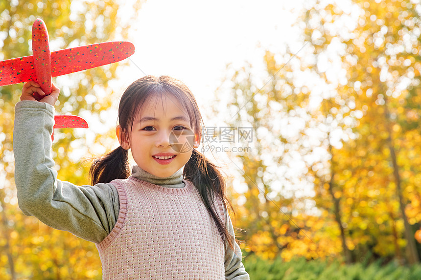 拿着玩具飞机在公园玩耍的小女孩图片