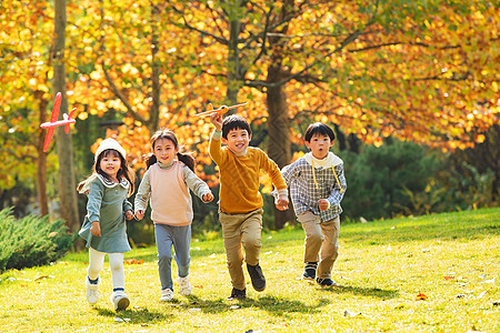 儿童跑步快乐儿童拿着玩具飞机在公园玩耍背景