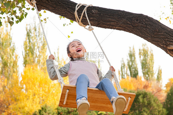 快乐的小女孩在公园里荡秋千图片