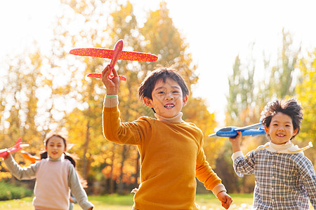 儿童飞拿着玩具飞机在公园玩耍的快乐儿童背景