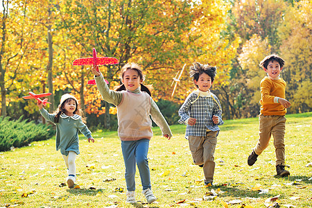 拿着玩具飞机在公园玩耍的快乐儿童图片