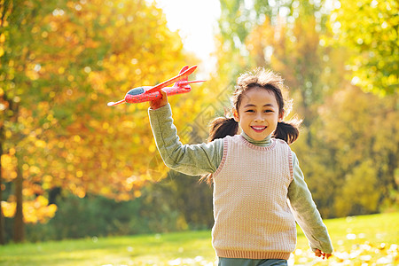 拿着玩具飞机在公园玩耍的小女孩图片