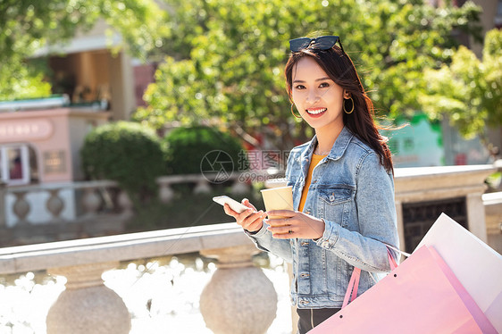 青年女人拿着手机逛街图片