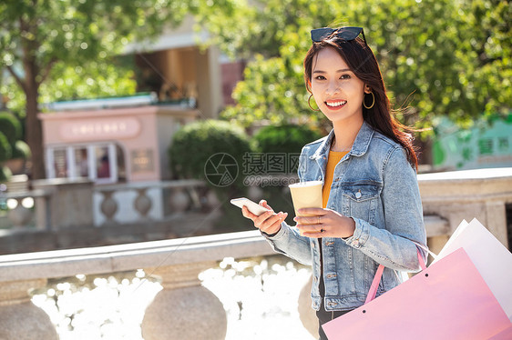 青年女人拿着手机逛街图片