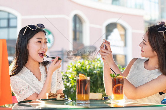 路边咖啡馆享受下午茶的闺蜜用手机记录生活图片