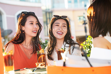 漂亮年轻的女孩们坐在路边咖啡馆聊天图片