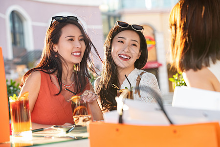 漂亮年轻的女孩们坐在路边咖啡馆聊天图片