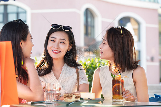 漂亮年轻的女孩们坐在路边咖啡馆聊天图片