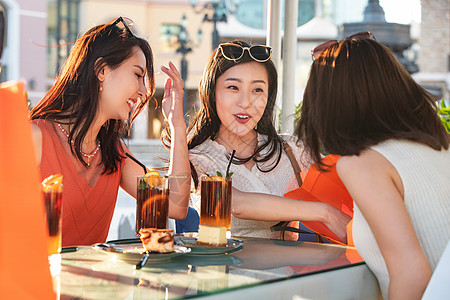 快乐的青年女人们坐在露天咖啡馆分享购物成果高清图片