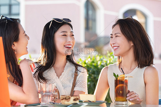 漂亮年轻的女孩们坐在路边咖啡馆聊天图片
