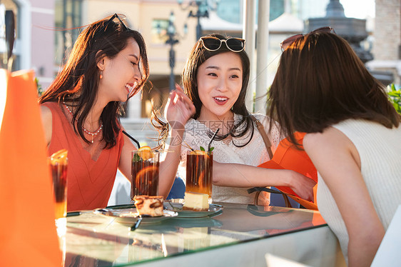 快乐的青年女人们坐在露天咖啡馆分享购物成果图片