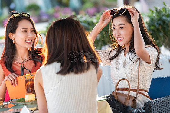 青年女人们坐在露天咖啡馆聊天图片