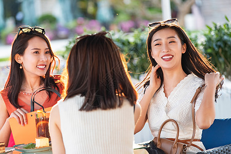 快乐的青年女人们坐在露天咖啡馆聊天图片