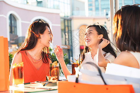 快乐的青年女人们坐在露天咖啡馆聊天图片