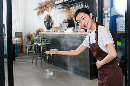 站着咖啡店门口做欢迎手势的女服务员图片