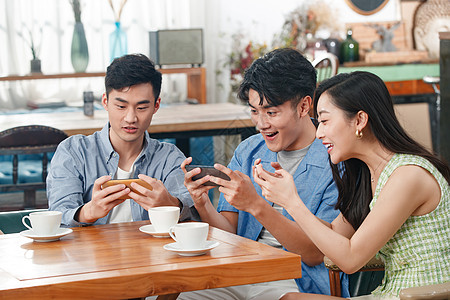 年轻朋友在咖啡馆里玩手机图片素材