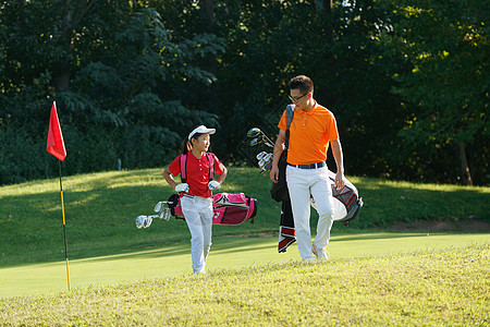 背着包男人球场上教练和学生背着高尔夫球包行走背景