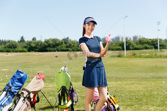 青年女人站在高尔夫球包旁图片