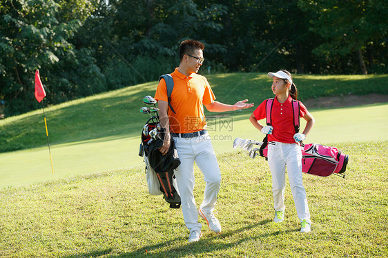 球场上教练和学生背着高尔夫球包交谈图片