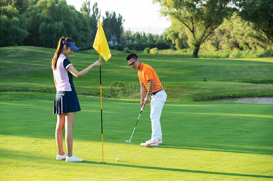 高尔夫球场上教练给青年女人做示范图片
