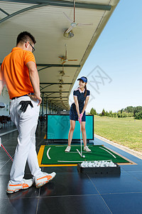 练习场上教练指导青年女人打高尔夫图片