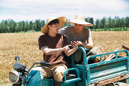 农民坐在三轮车上使用手机图片