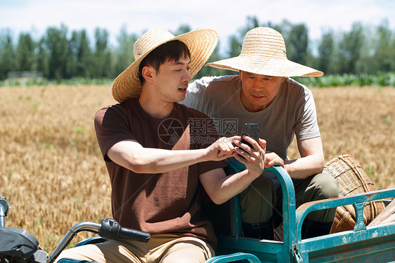 农民坐在三轮车上使用手机图片