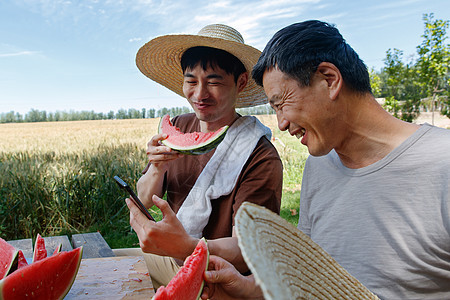 农民在田地旁休息吃西瓜图片