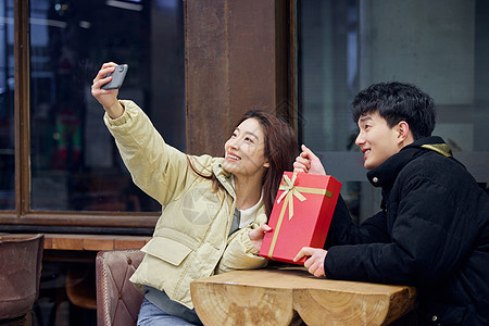 年轻情侣拿着礼物盒自拍图片