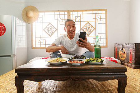 老年人坐在家里吃饭看手机图片