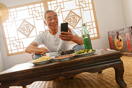 新农村房屋老年人坐在家里吃饭看手机背景