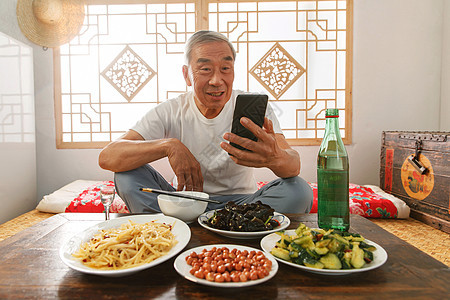 老年人坐在家里吃饭看手机图片