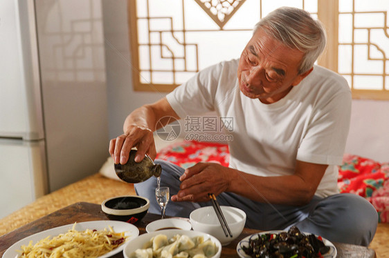 老年人坐在家里喝酒吃饭图片