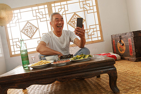 老年人手机老年人坐在家里吃饭看手机背景