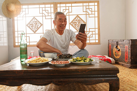 中国白酒老年人坐在家里吃饭看手机背景