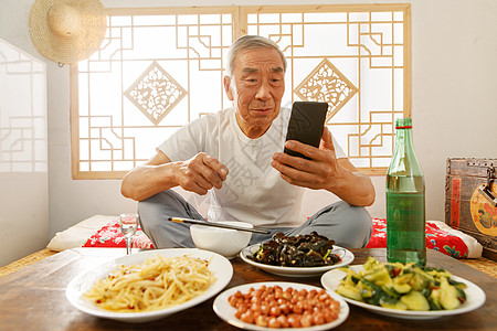 老年人坐在家里吃饭看手机图片