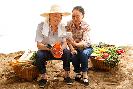 农民夫妇坐在田头看手机高清图片